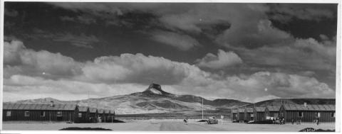 Black and white image of military-style barracks with Heart Mountain in the background