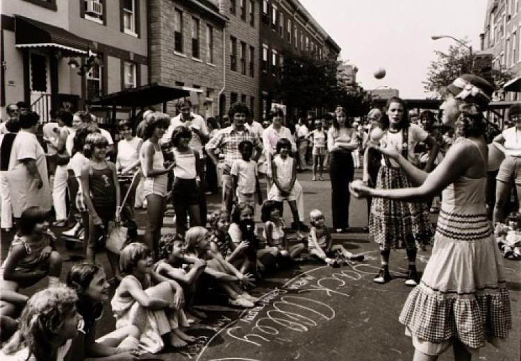 A woman juggling in front of neighborhood children in Baltimore, MD (ca. 1975). Photograph by Joan Clark Netherwood.