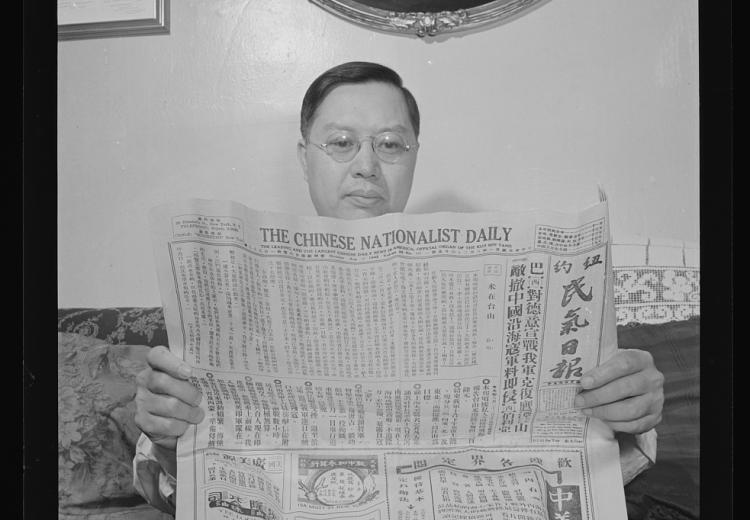 Man sitting on a couch reading a newspaper