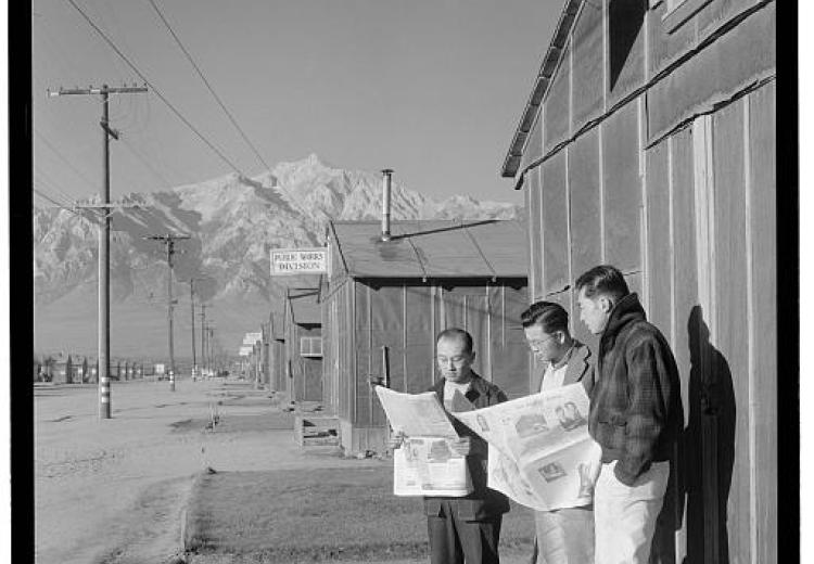 Roy Takeno (Editor) and group reading Manzanar paper [i.e. Los Angeles Times] in front of office, Yuichi Hirata, Nabuo Samamura, Manzanar Relocation Center, California